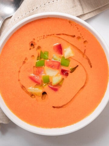 large bowl of gazpacho garnished with apple and tomato.