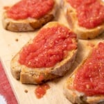 several slices of toasted bread topped with a grated tomato mixture.