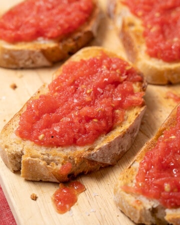 several slices of toasted bread topped with a grated tomato mixture.