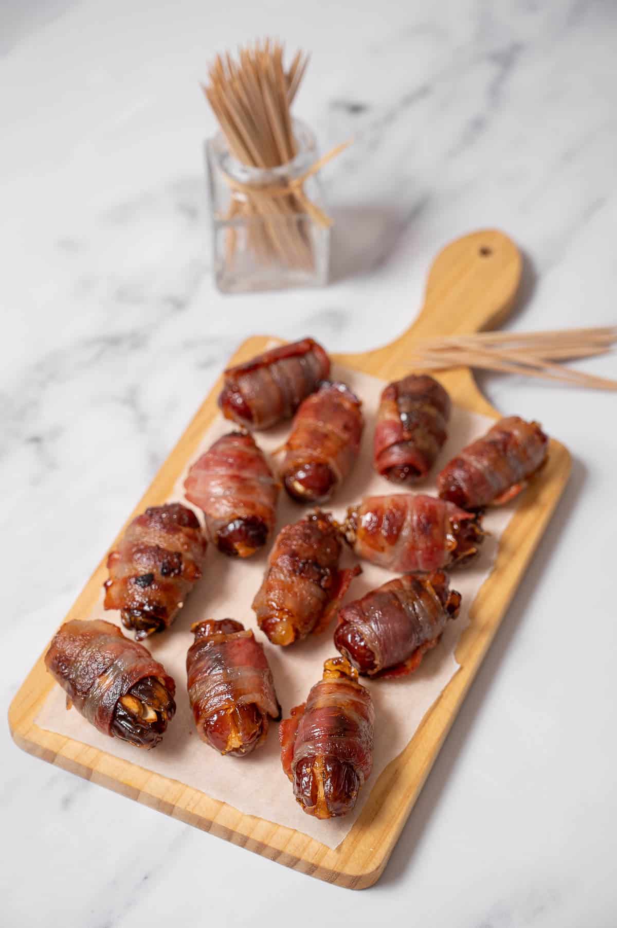 bacon wrapped dates on a cutting board.