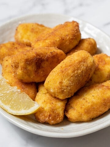 plate of cod croquettes with a wedge of lemon.