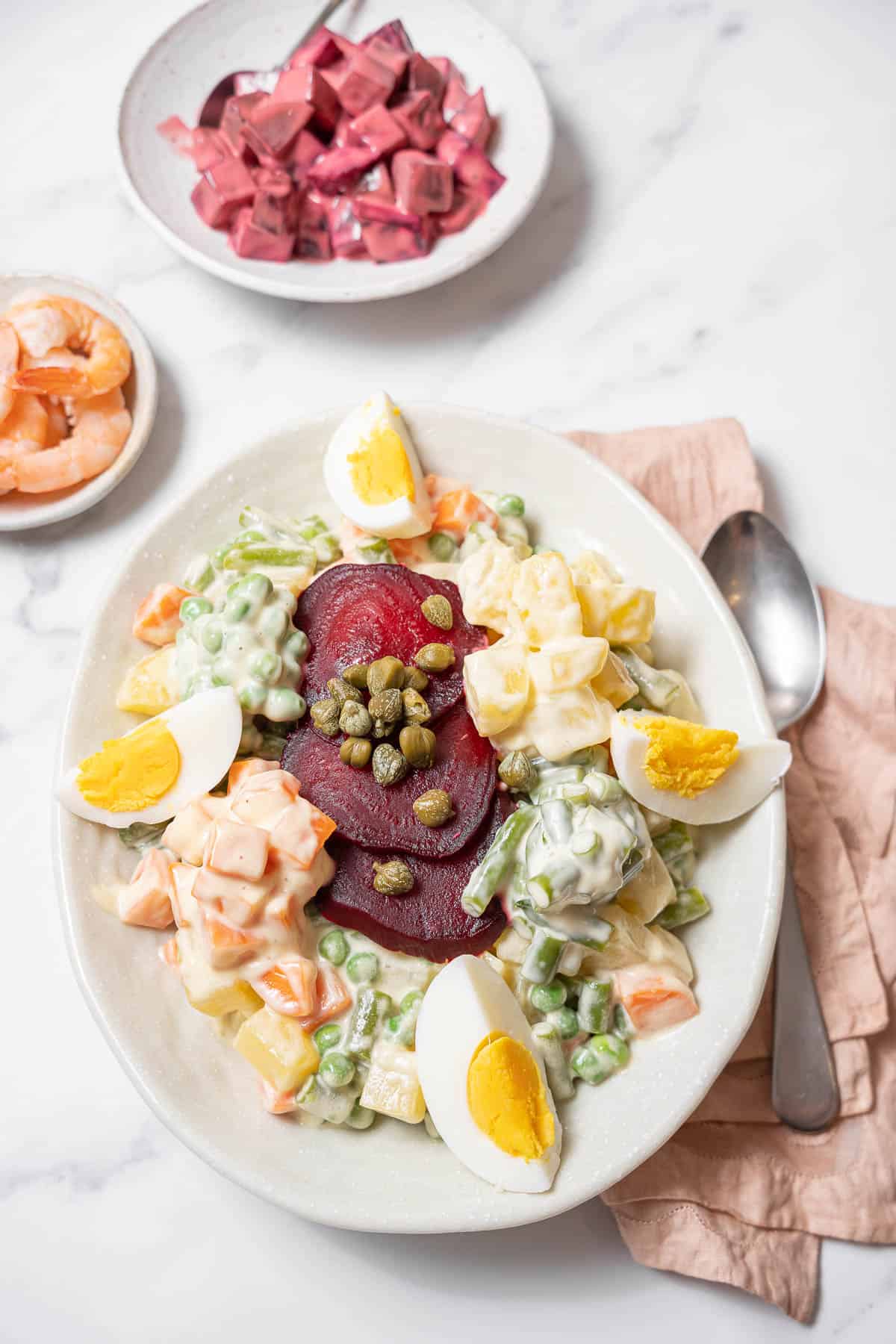 plate of ensaladilla rusa with boiled shrimp and beets.