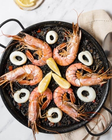dish of black paella with a serving spoon.