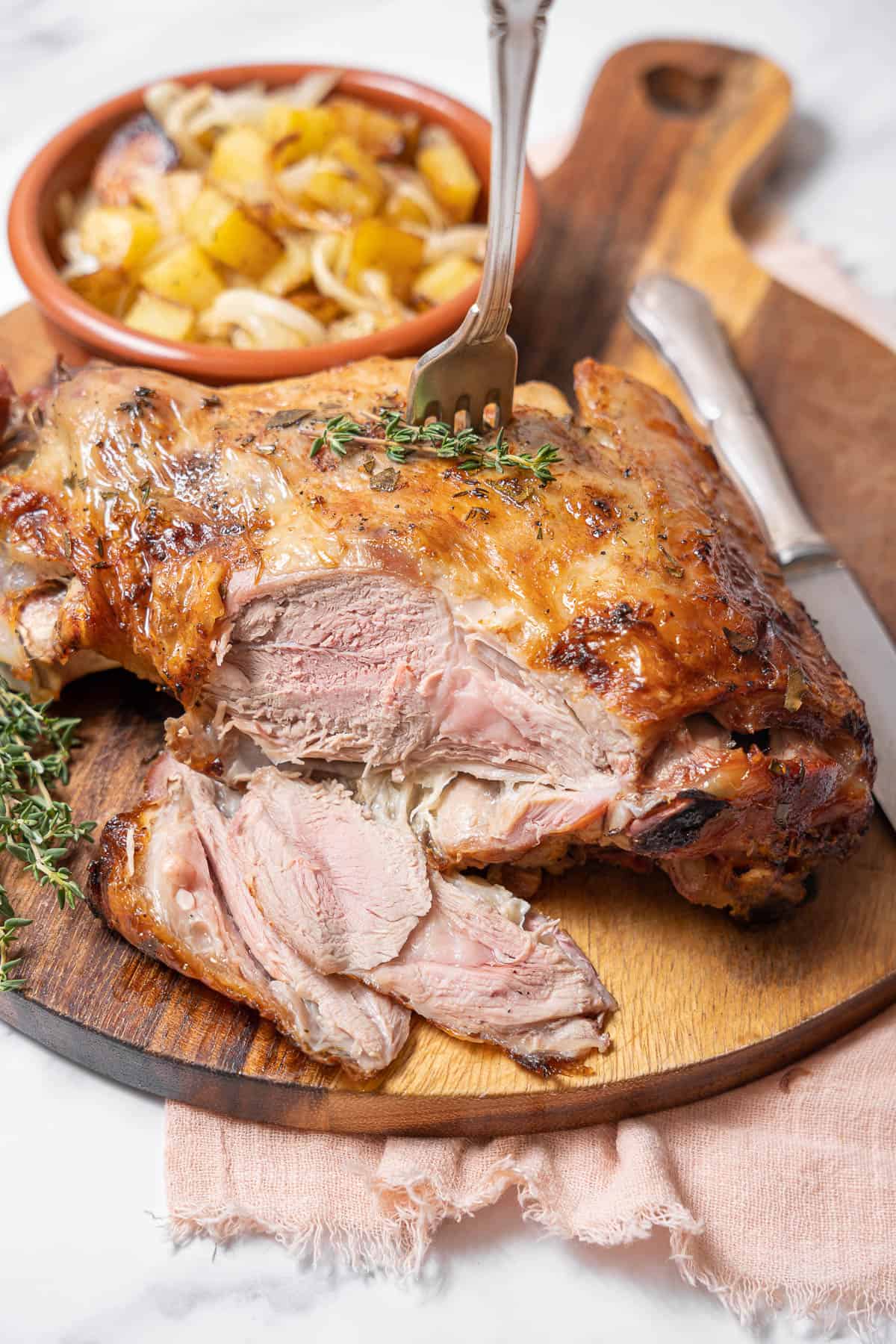 sliced roasted lamb on a wooden cutting board.