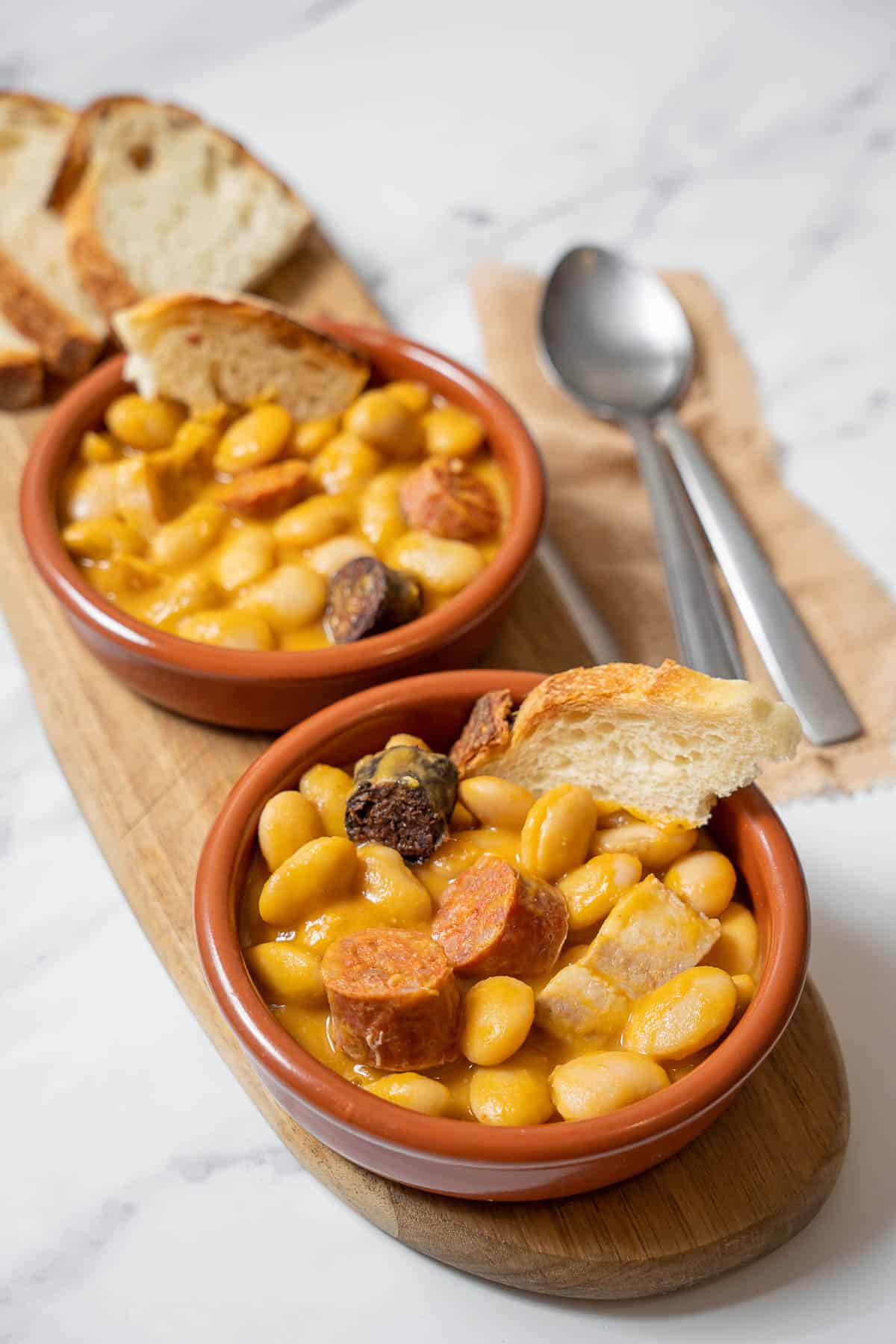 bowls of fabada with sliced bread dipped in.