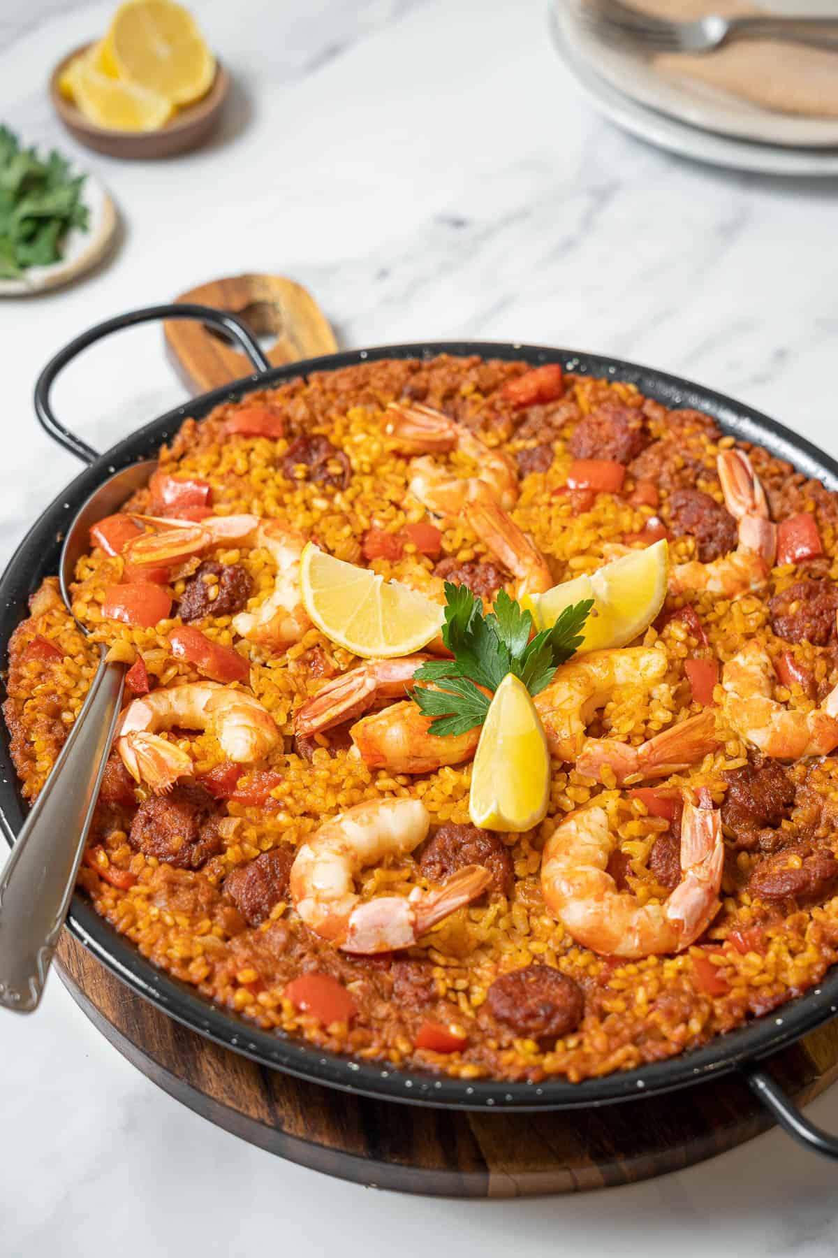 serving the prawn and chorizo paella with a large spoon.