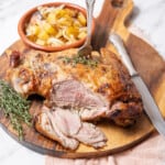 serving the roasted lamb on a large wooden cutting board.