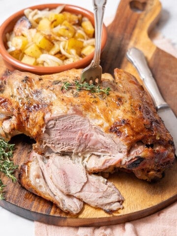 serving the roasted lamb on a large wooden cutting board.