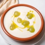 bowl of ajo blanco topped with olive oil and grapes.
