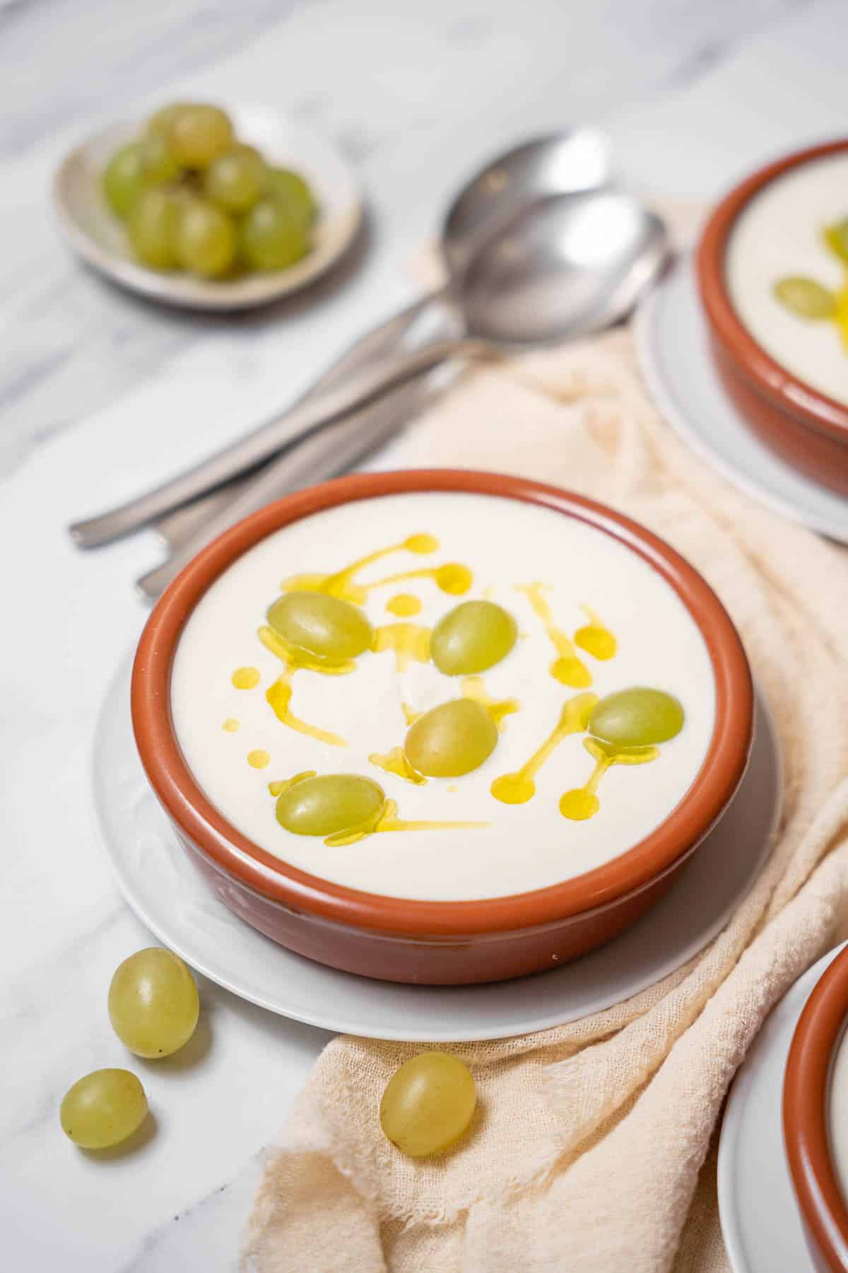 bowl of ajo blanco with spoons and green grapes.