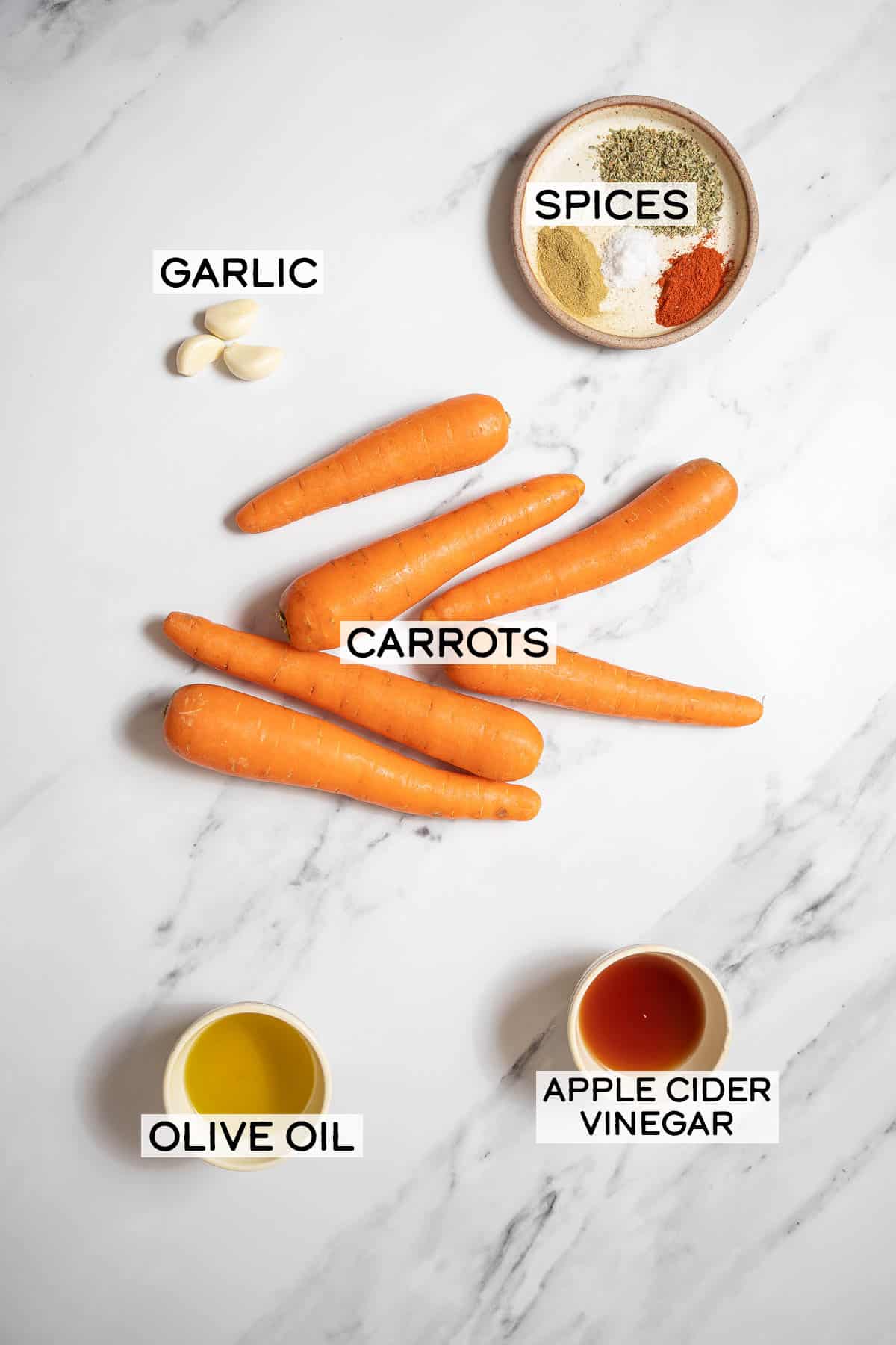ingredients for marinated carrots on a marble counter.