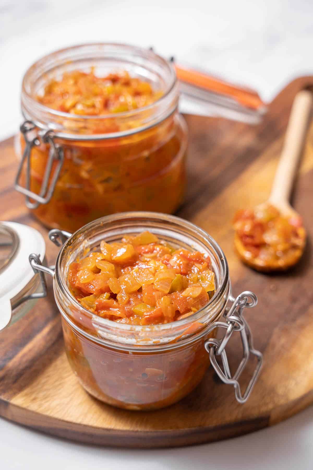 two jars of Spanish sofrito with a wooden spoon.