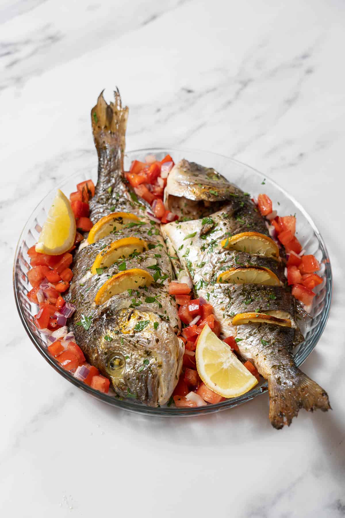 two baked bream with tomato salad.