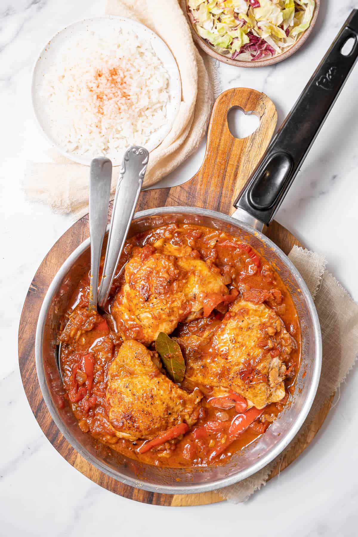 skillet of chicken chilindrón with rice and salad.
