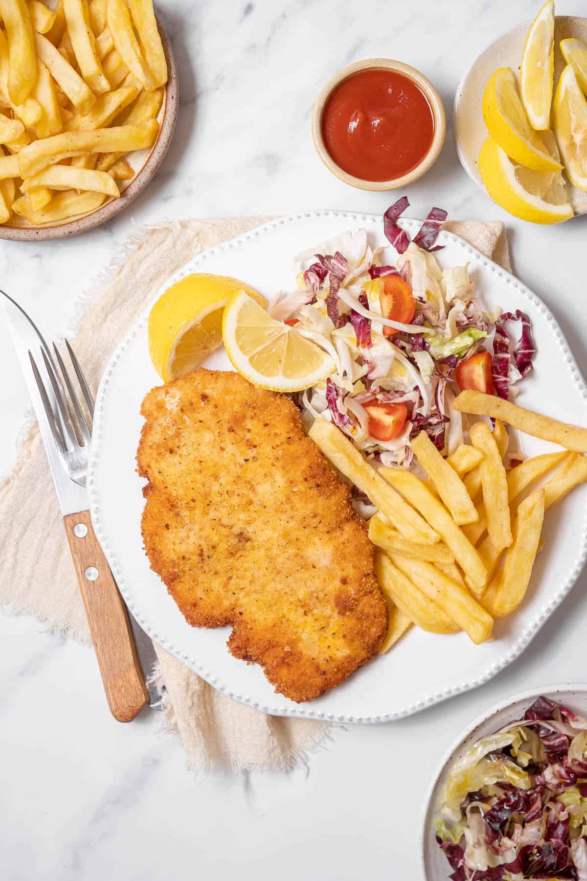 chicken milanesa with french fries and salad.