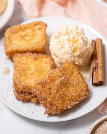 serving the leche frita with ice cream and a cinnamon stick.