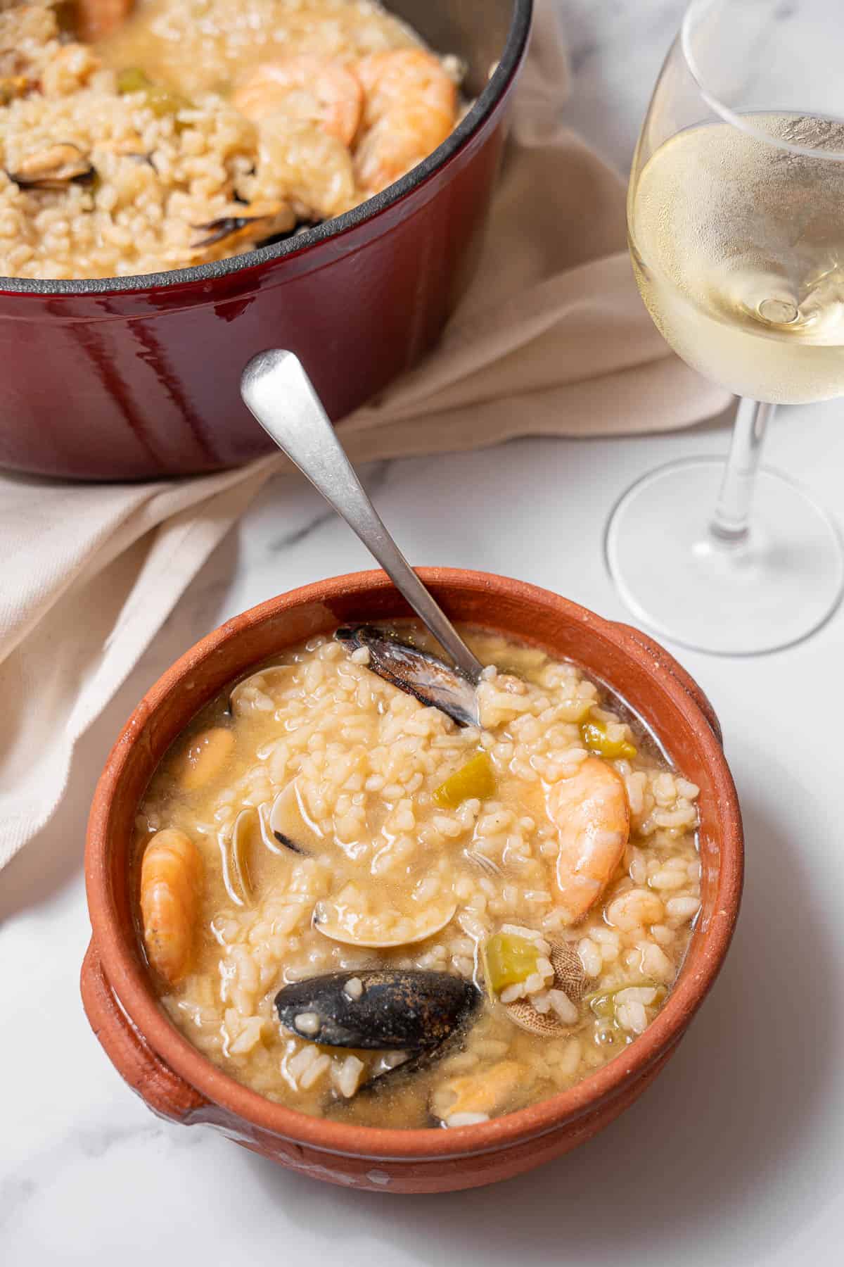 bowl of seafood rice with a glass of wine.