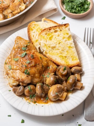 plate of chicken and mushrooms with sliced bread.