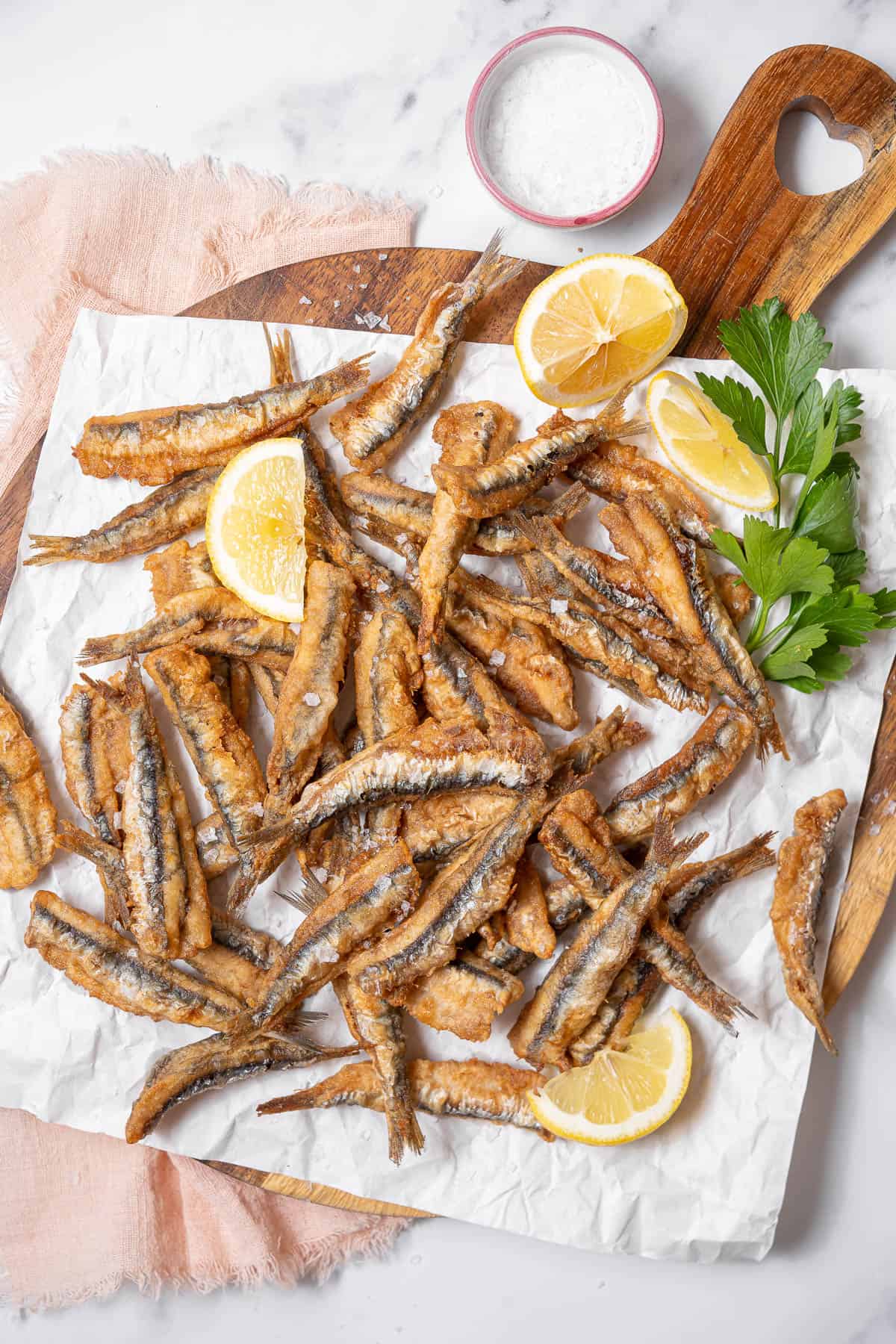 platter of fried anchovies with lemon slices.