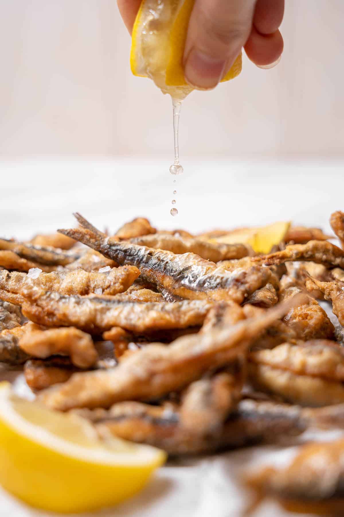 squeezing lemon juice on fried anchovies.