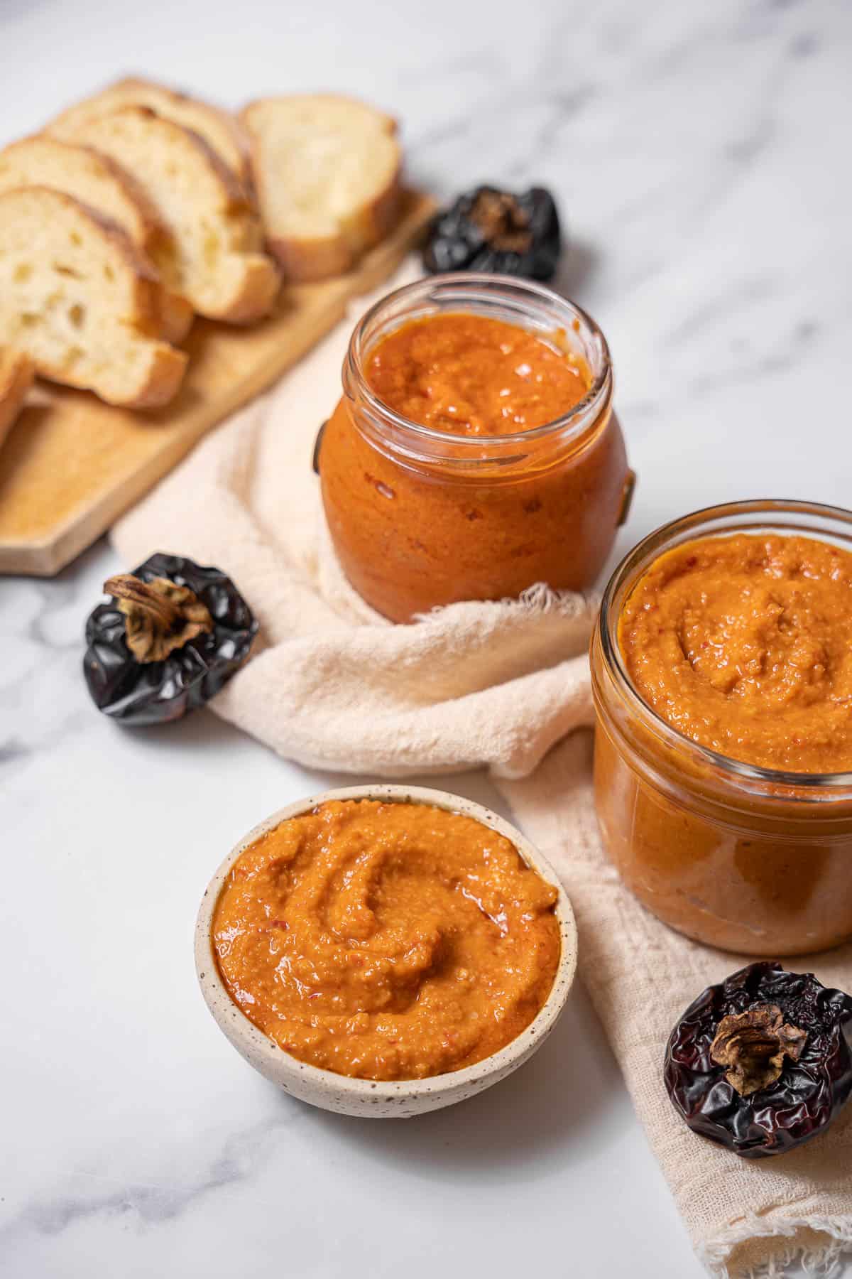 jars of romesco sauce with ñora peppers and bread.