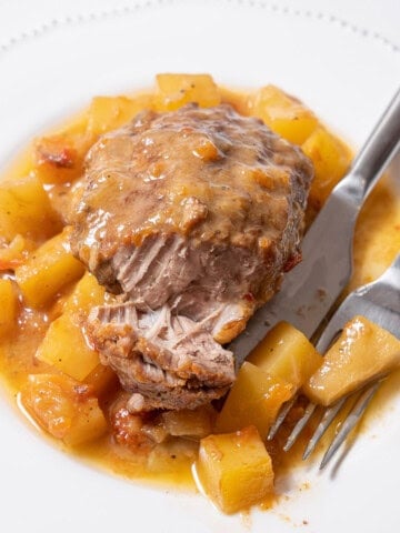plate of braised pork cheek with potatoes and a fork.