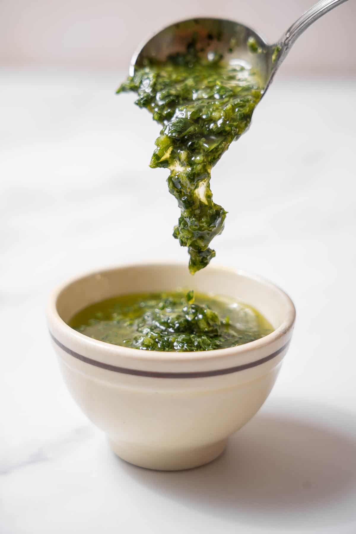 pouring a spoonful of mojo verde into a bowl.