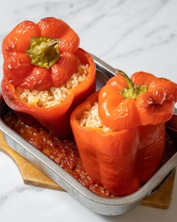 two stuffed peppers in a small pan with sauce.