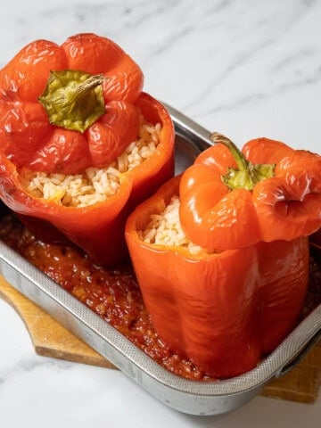 two stuffed peppers in a small pan with sauce.