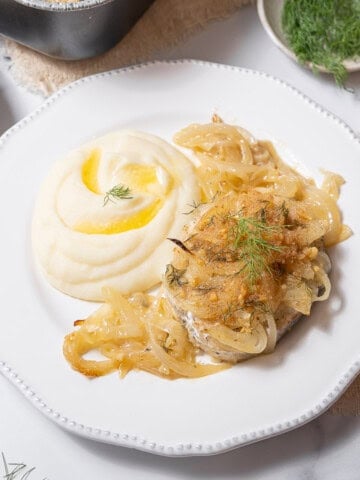 plate of hake with onions and dill.