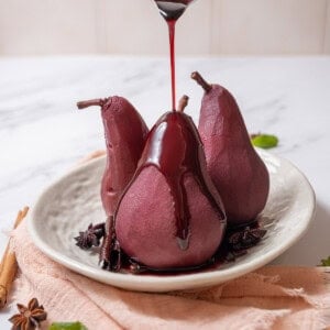 pouring red wine sauce on poached pears.