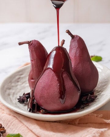 pouring red wine sauce on poached pears.