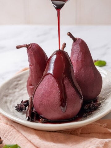 pouring red wine sauce on poached pears.