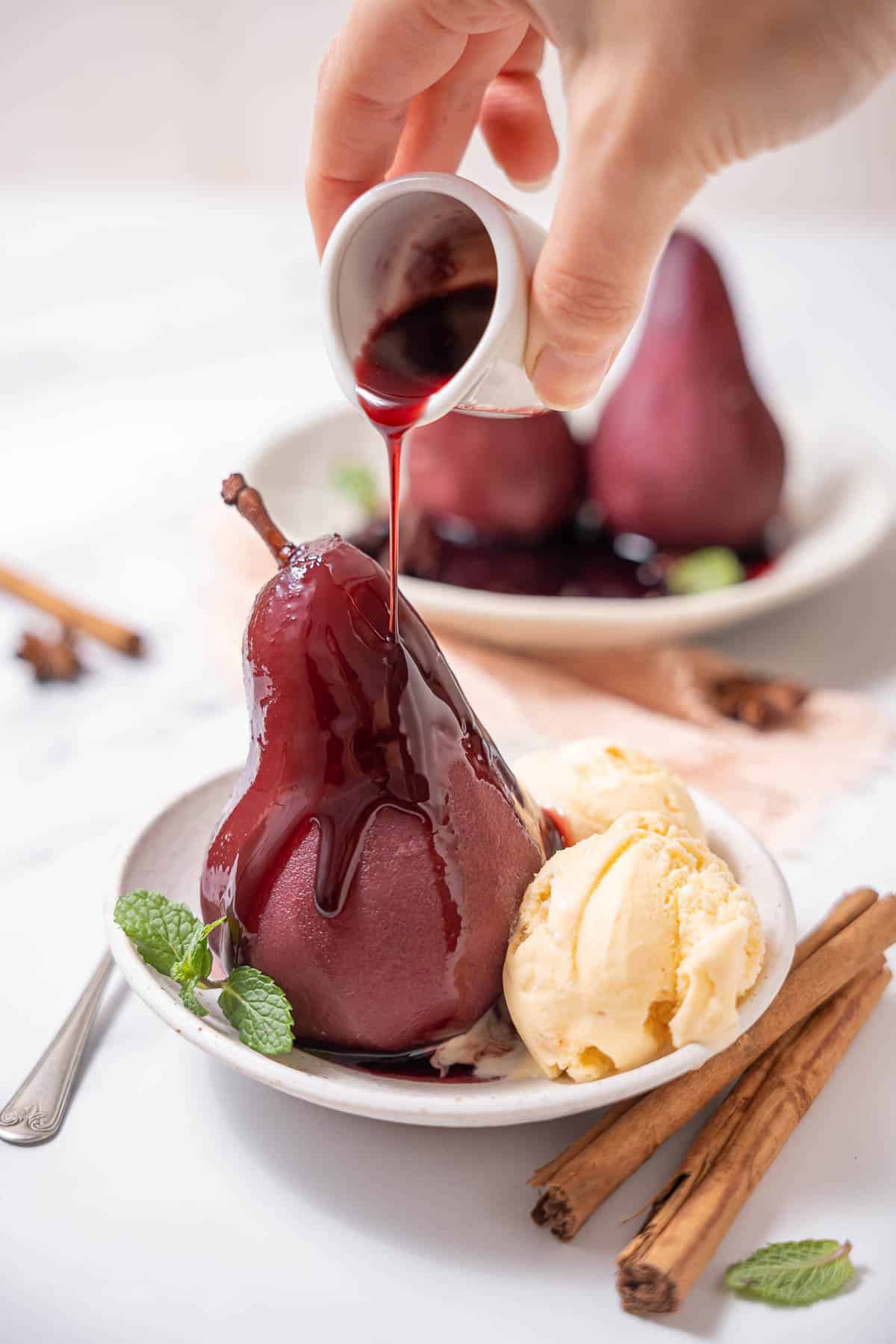 pouring red wine sauce on poached pears.