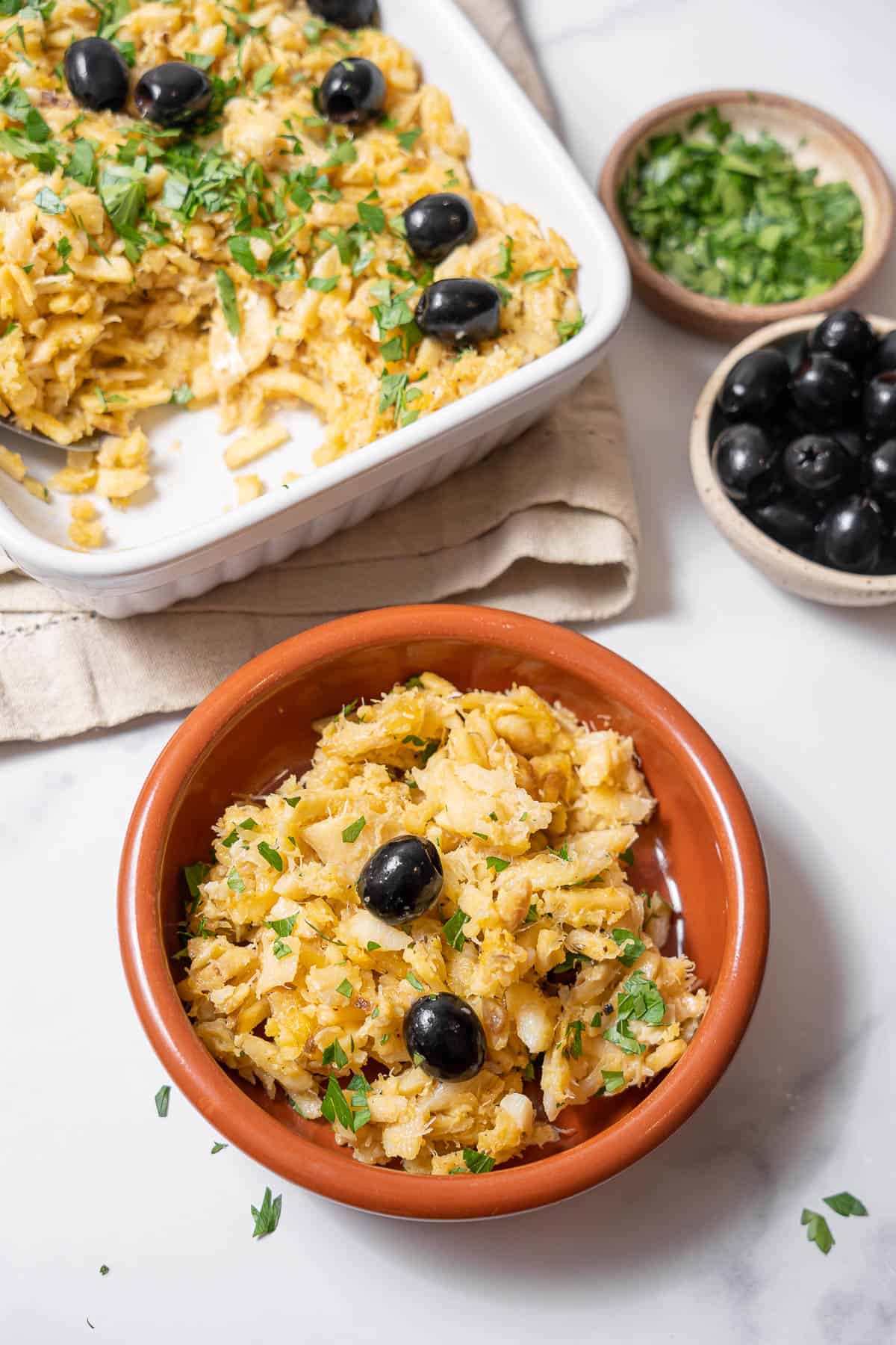 serving bacalhau a bras with olives and parsley.