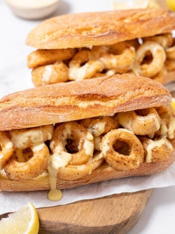 two fried calamari sandwiches on a board.