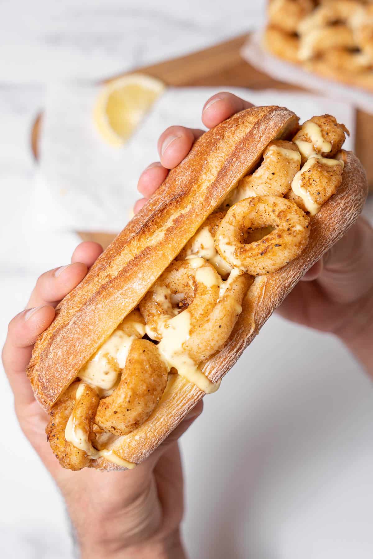 holding a fried calamari sandwich.