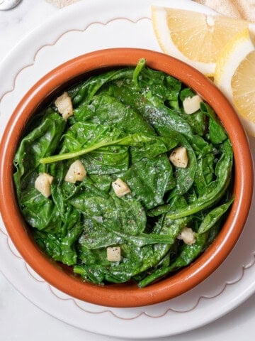 bowl of spinach with garlic and lemon.