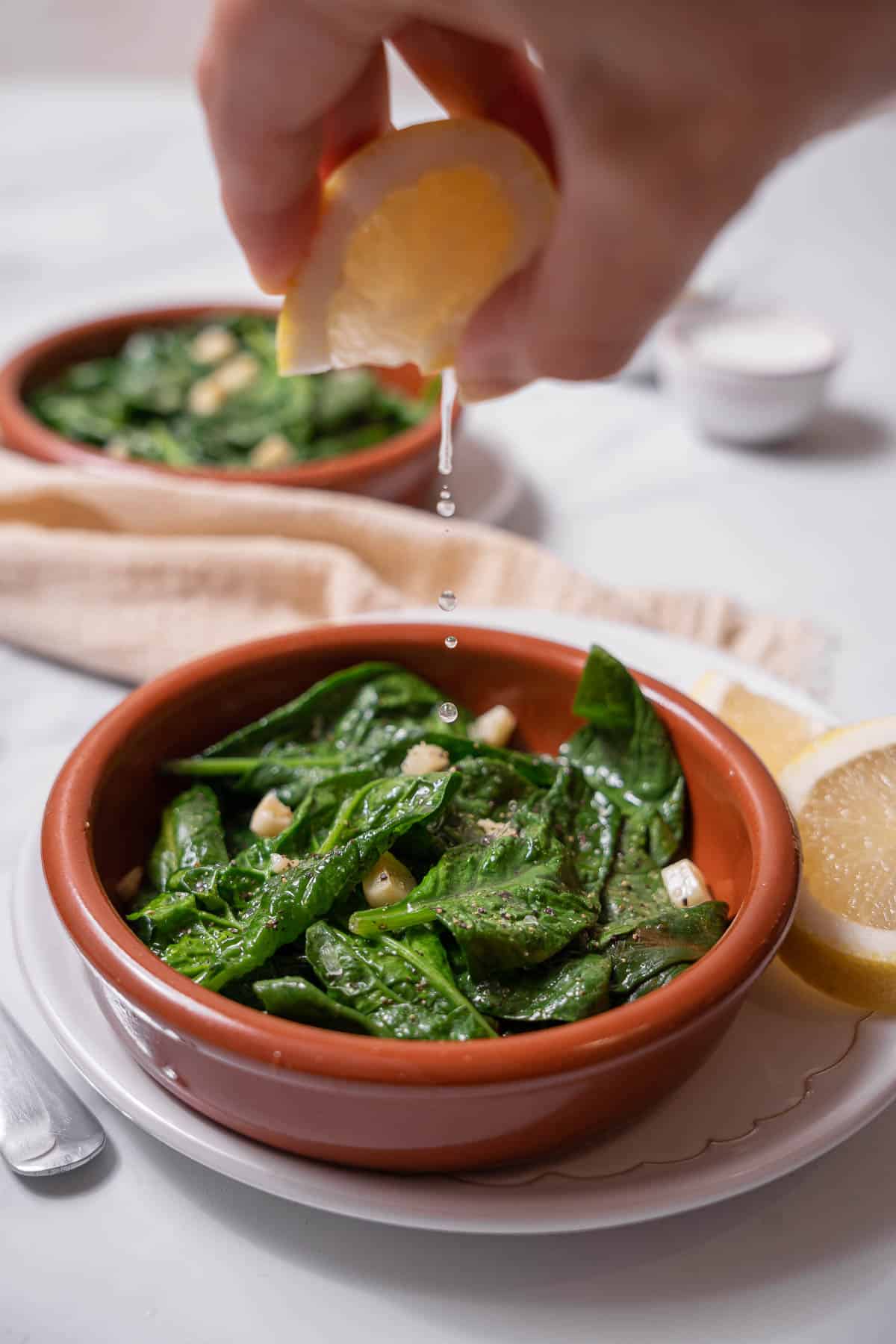 squeezing lemon juice on cooked spinach.