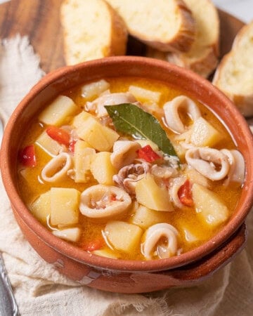 bowl of squid and potato stew with bread.