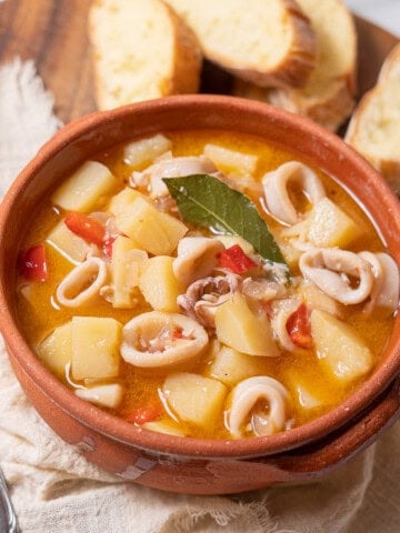 bowl of squid and potato stew with bread.