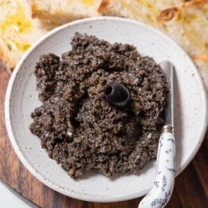 bowl of black olive tapenade with a knife.