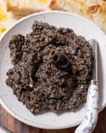 bowl of black olive tapenade with a knife.