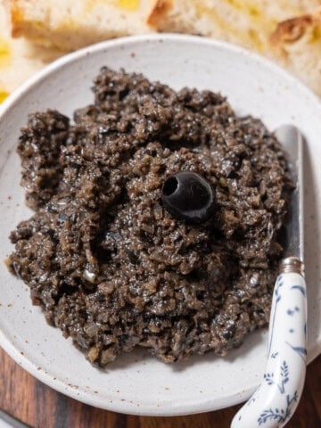 bowl of black olive tapenade with a knife.