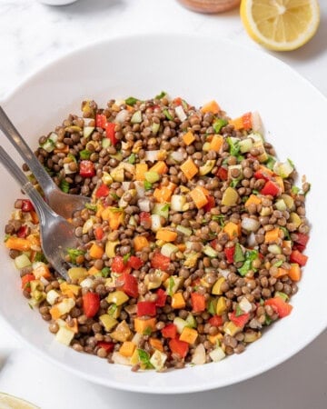 bowl of lentil salad with serving utensils.