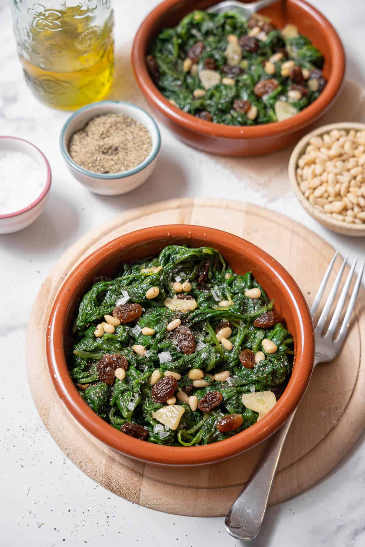 bowl of spinach with pine nuts with a fork.