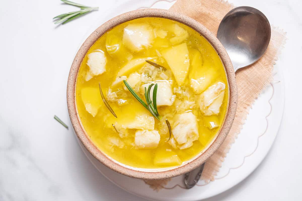 bowl of cod and potato stew with a spoon.