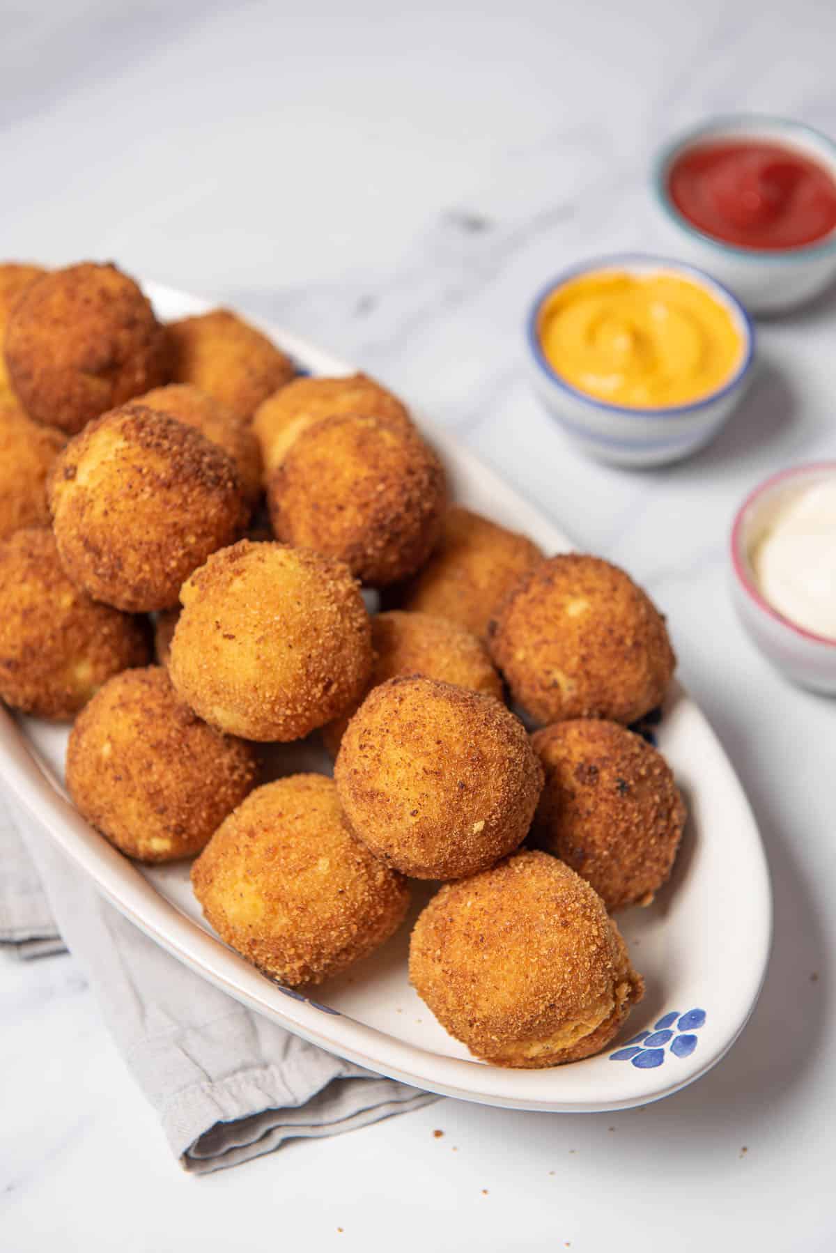 potato croquettes with bowls of sauces.