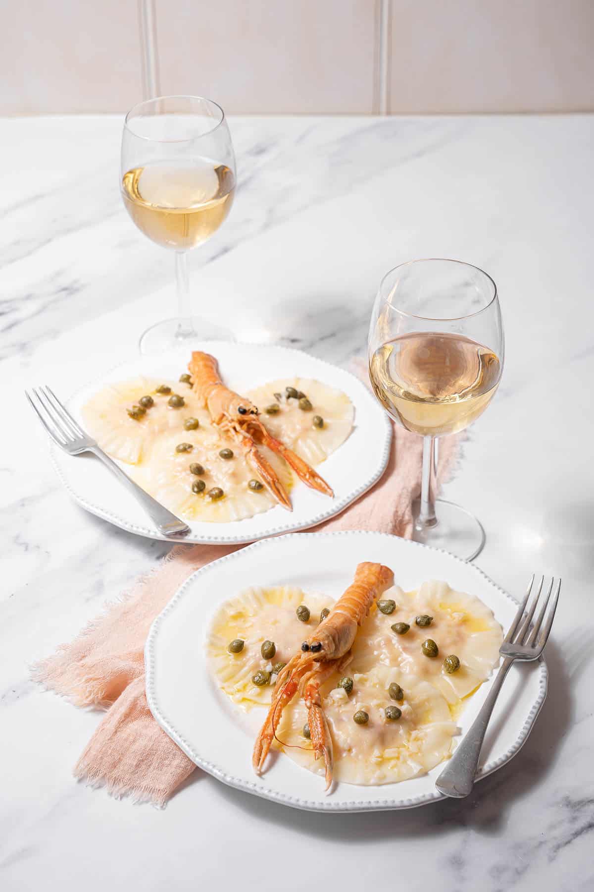 two plates of langoustine ravioli with white wine.